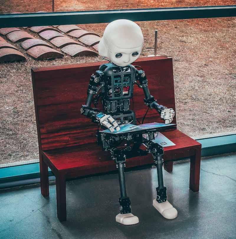 robotti istuu penkillä ja lukee