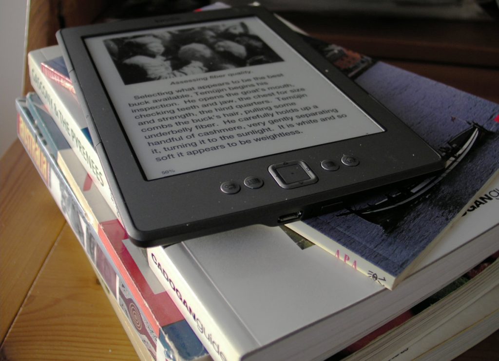 e-kirjojen lukulaite Kindle paperikirjapinon päällä